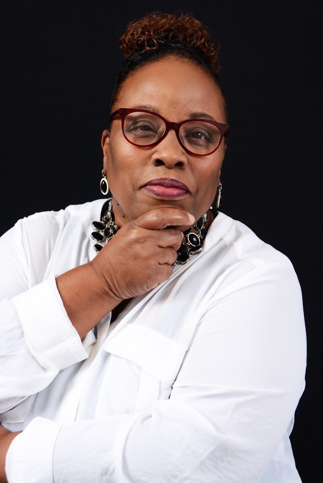 Pastor Joyce Davis wearing a white blouse against a dark studio background